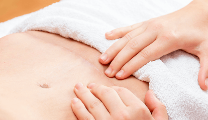 Manos haciendo presión en abdomen de paciente